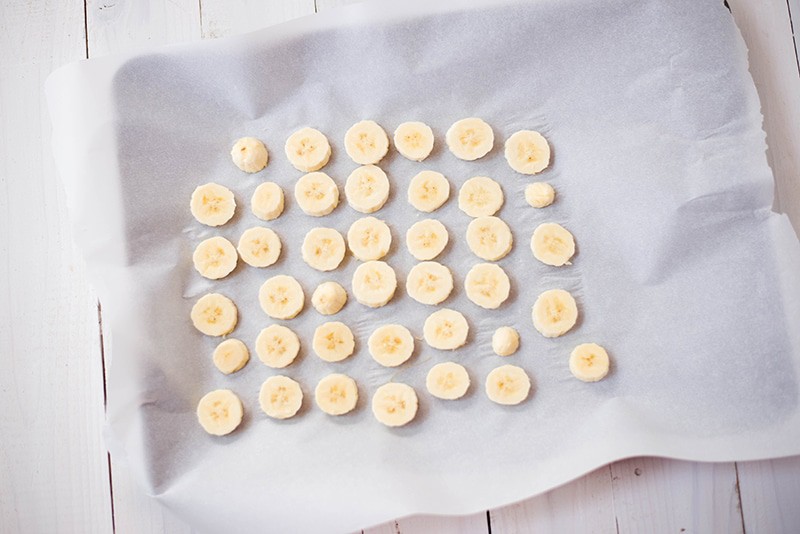 Frozen banana slices placed on a lined baking tray to be used for banana ice cream recipe 