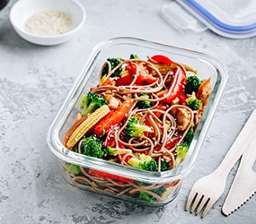 Meal prep containers with broccoli, carrots, rice or soba noodles