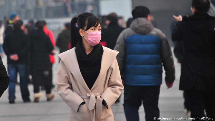 Tourists wearing face masks against air pollution visit the Bund along the Huangpu River in heavy smog in Shanghai, China