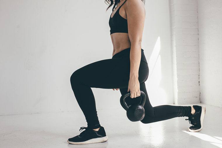Woman lunging with kettle bells