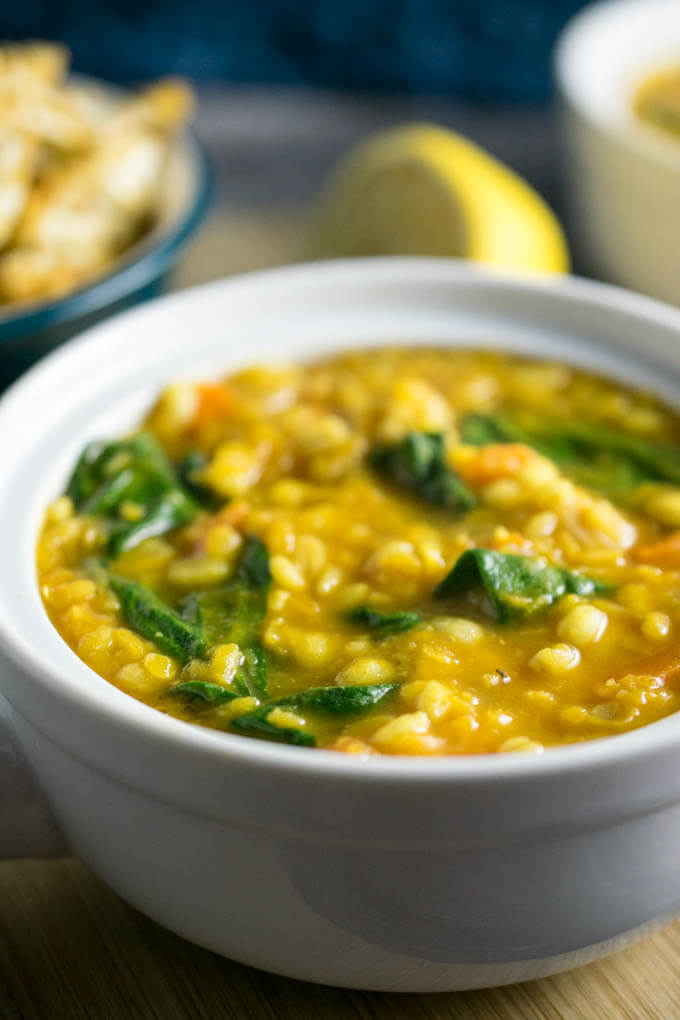 Closeup of a warming golden lentil soup with onion, red lentils, pearl barely, and wilted delicate spinach perfect for winter evenings