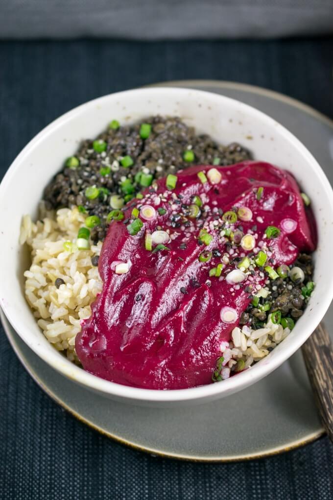 A ceramic bowl with Peruvian spiced beluga lentils, brown rice, and bright red beet puree